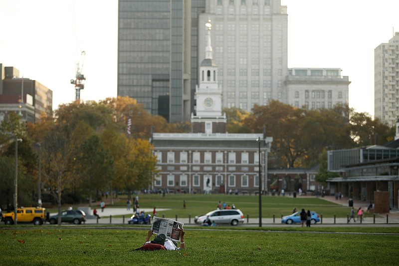A man reads a newspaper near Independence Hall, Friday, Nov. 6, 2015, in Philadelphia. America's birthplace has been named the country's first World Heritage City. The Organization of World Heritage Cities voted in Peru on Friday to add Philadelphia. The city qualifies because Independence Hall is a UNESCO World Heritage Site. (AP Photo/Matt Slocum)