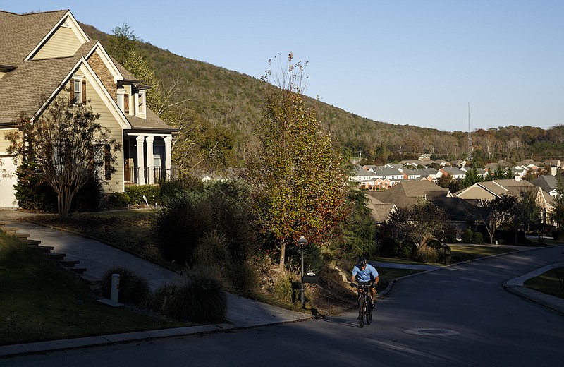 A cyclist rides past homes in the Black Creek Mountain development Tuesday, Nov. 10, 2015, in Chattanooga, Tenn.