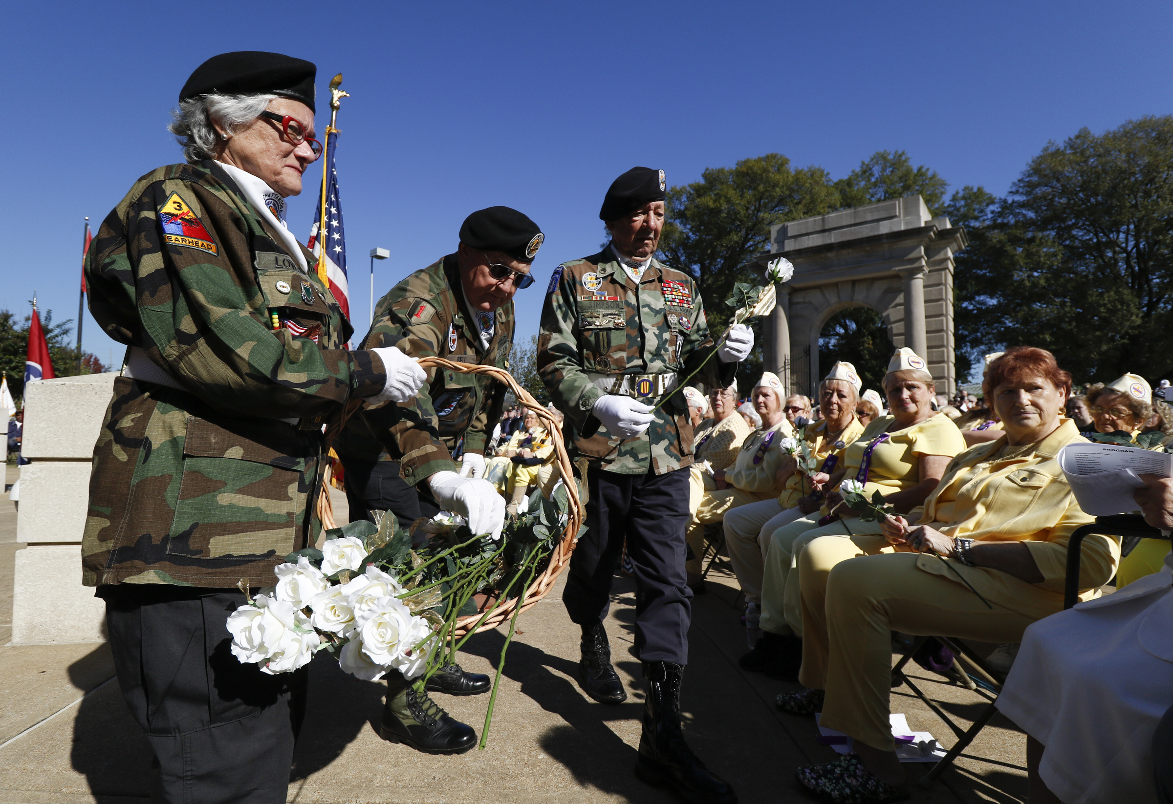Staff Photo by Dan Henry / The Chattanooga Times Free Press- 11/11/15. Honor Gurad members Marsha Thibadoux, Rick Simpson and David Bell, from left, hand out white roses to Gold Star Mothers and Wives during a special Veteranճ Day tribute on November, 11, 2015 at the Chattanooga National Cemetery Armed Forces Pavillon. The Chattanooga National Cemetery and the Chattanooga Area Veterans Council hosted the event.
