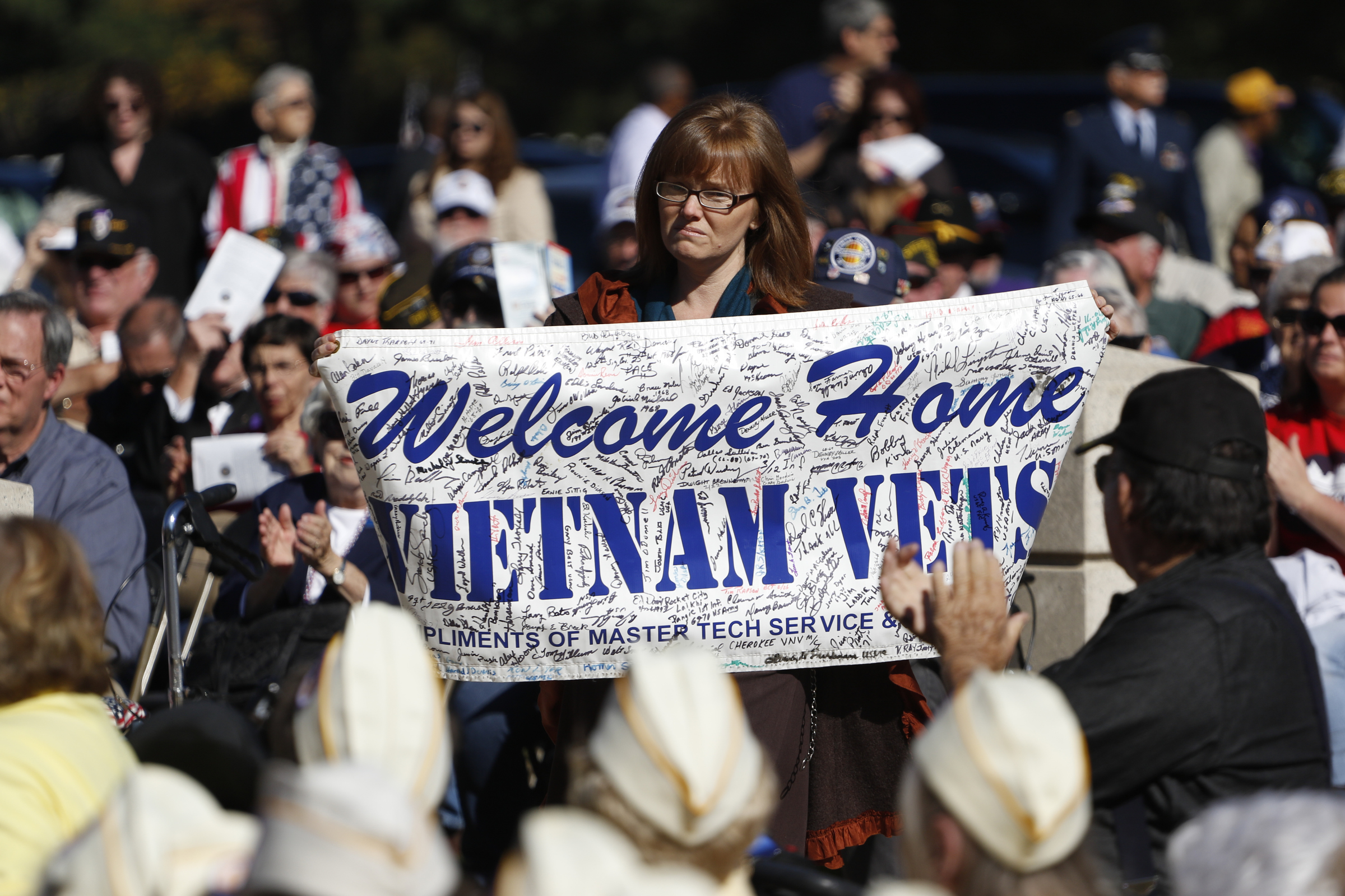 Staff Photo by Dan Henry / The Chattanooga Times Free Press- 11/11/15. Stacey Griffin walks in with a sighed sign during the Veteranճ Day tribute on November, 11, 2015 at the Chattanooga National Cemetery Armed Forces Pavillon. The Chattanooga National Cemetery and the Chattanooga Area Veterans Council hosted the event.