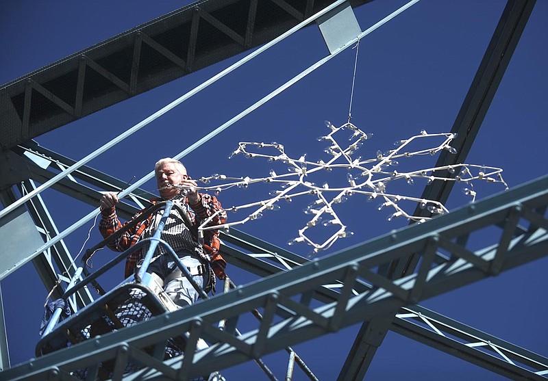 Mark Sivley, with Triad Electric, hangs snowflakes on the Walnut Street Bridge Thursday, Nov. 12, 2015.