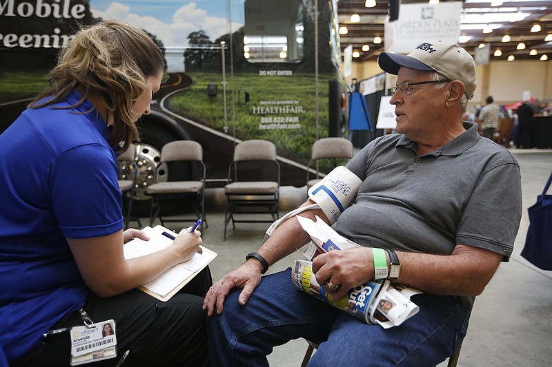 Amanda Smith, left, takes the blood pressure of John Soy at the Erlanger booth at the 2014 Life Expo.