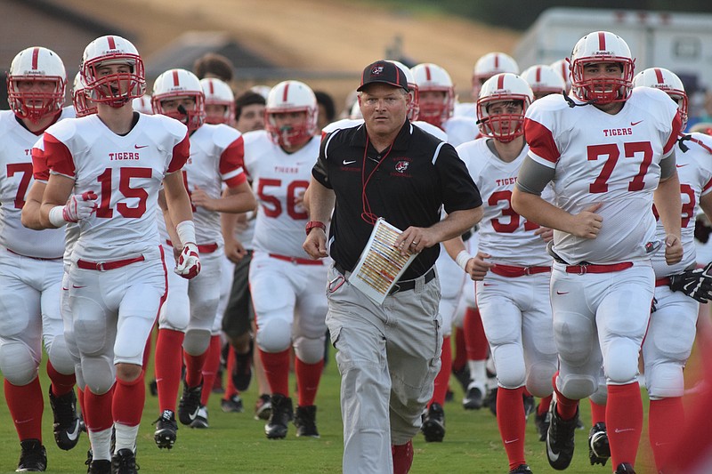 Whitwell coach R.C. Helton leads the Tigers onto the field in an early-season game. Their season ended Friday in the second round of the state playoffs.