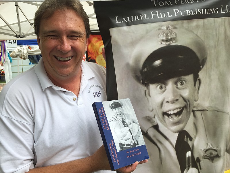 
              In this undated photo, historian Tom Perry shows off the new book he co-authored with David Browning, "My Life as The Mayberry Deputy: We Have Extra Security Tonight!" at a recent festival in Wytheville, Va. The book is Browning's autobiography, but not long ago, Perry released his own memoir, "Beyond Mayberry." That book is a tribute to the late Andy Griffith, an actor who grew up in Mount Airy, a city which served as the real-life inspiration for the TV show's Mayberry. (Joe Tennis/The Bristol Herald-Courier via AP) MANDATORY CREDIT
            