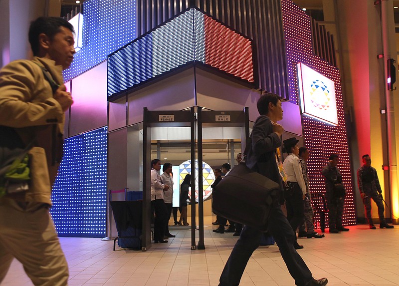 
              Journalists walk past the main entrance of the International Media Center of the upcoming APEC (Asia Pacific Economic Cooperation) Summit of Leaders which is lit with the colors of the French national flag in solidarity with the French people following Friday's terrorist attacks in Paris, Saturday, Nov. 15, 2015 in Manila, Philippines. Thousands of police and soldiers are mobilized for the annual summit of the APEC which is slated Nov. 18-19, 2015. (AP Photo/Lino G. Escandor II)
            