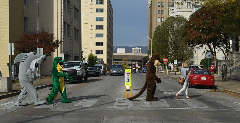 Shannon Colbert, with the Tennessee Aquarium, leads costumed characters across 11th Street on the way to a press conference Monday, November 16, 2015 at the City Hall to announce #CHAgives Day, which will be the Tuesday after Thanksgiving.