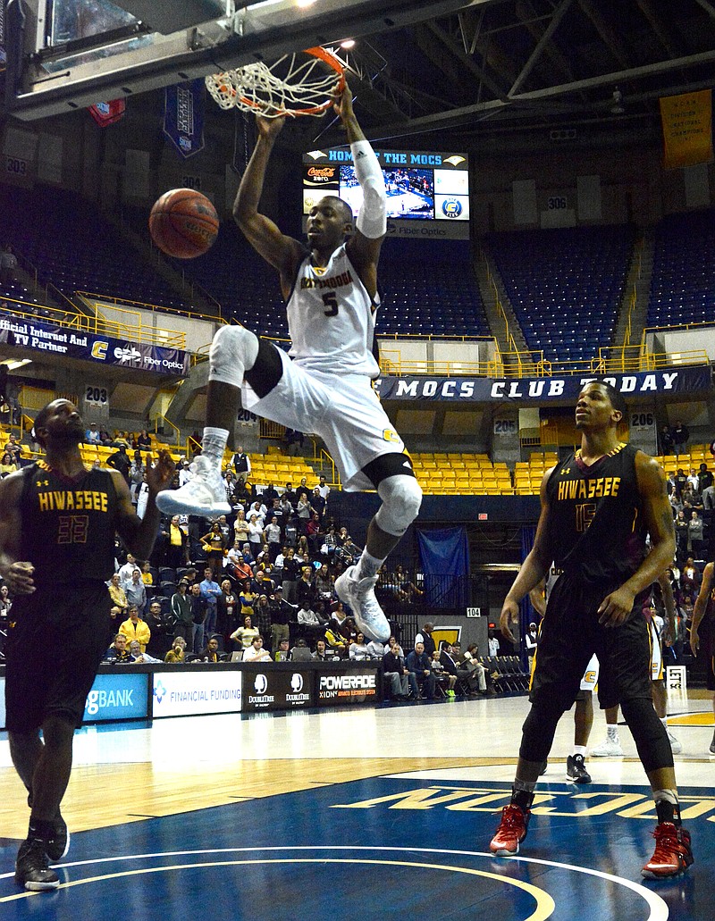 UTC's Justin Tuoyo hangs on the rim after making a slam dunk while Hiwassee's Jordan Sexton, left, and Aario Johnson look on as the University of Tennessee at Chattanooga hosts Hiwassee College in a men's basketball game Monday, Nov. 16, 2015, in Chattanooga, Tenn. UTC won their home opener by a score of 94-55.