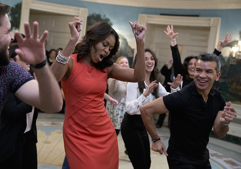 
              First lady Michelle Obama dances to Gloria Estefan's "Conga" in the Diplomatic Room of the White House in Washington, Monday, Nov. 16, 2015, during a Broadway at the White House event for high school students involved in performing arts programs. She is joined by Sergio Trujillo, Colombian dancer and choreographer, right, and Josh Segarra, left.  (AP Photo/Carolyn Kaster)
            