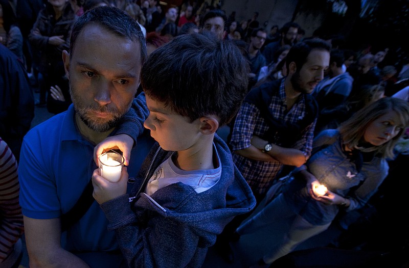 
              FILE- In this Monday, Nov. 16, 2015, file photo, a man holds a child in his arms outside of the French embassy in Mexico City during a vigil for the victims of the terrorist attacks in Paris. After the France terror attacks, schools and parents around the world are grappling with what to say to children, and how to say it. From country to country, the topic was tackled in different ways. (AP Photo/Marco Ugarte, File)
            
