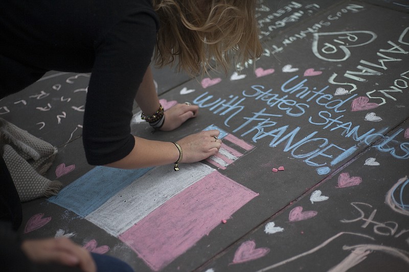 People write messages with chalk at Republic Square, where makeshift memorials were set up, three days after terrorist attacks in Paris.