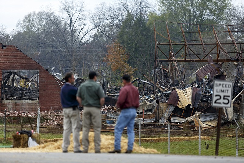 Men stand looking at the burned wreckage of the Barwick Mills building Tuesday, Nov. 17, 2015, three days after a fire destroyed much of the building in Lafayette, Ga. The EPA has been taking air samples to assess the impact of the fire.