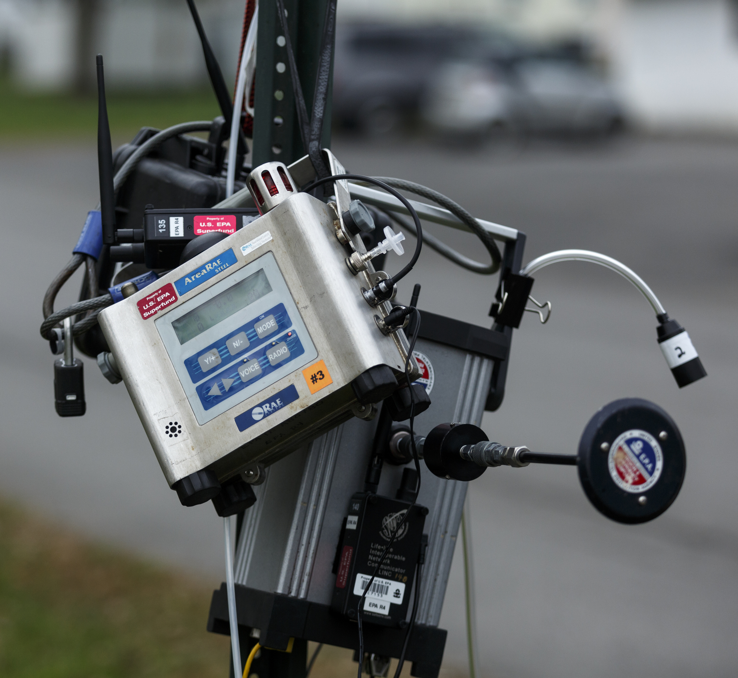 An EPA monitoring device hangs from a stop sign at the intersection of South Chattanooga Street and McLemore Street on Tuesday, Nov. 17, 2015, three days after a fire destroyed much of the Barwick Mills building in Lafayette, Ga. The EPA has been taking air samples to assess the impact of the fire.