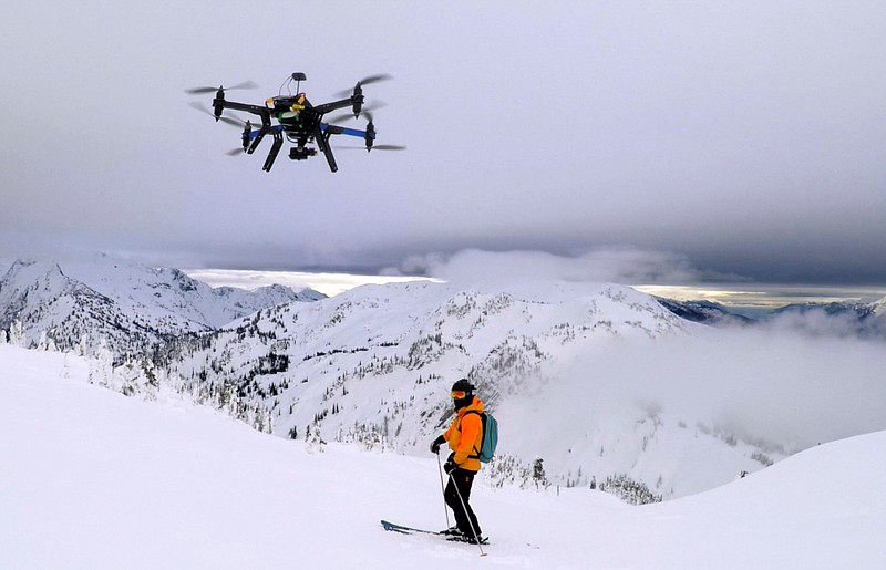 
              This Dec. 2014 photo shows a drone hovering by a skier as he makes his way down mountainside at resort at Revelstoke, B.C., Canada. Some US ski resorts are exploring the possibility of "drone zones" where professionally operated drones can produce customized video that show off individuals skiers in action. (Jason Soll/Cape Productions via AP)
            