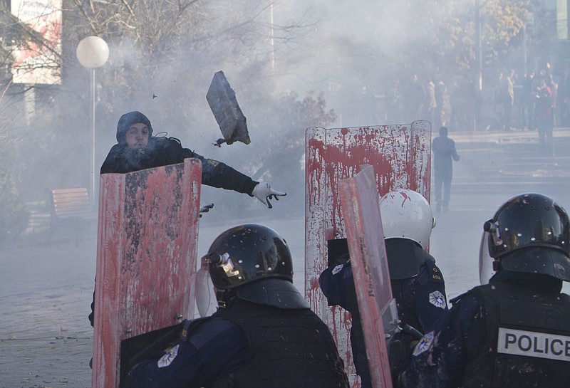 
              A supporter of the opposition parties in Kosovo throws a rock towards police in riot gear securing Kosovo's parliament building, in capital Pristina on Tuesday, Nov. 17, 2015. Kosovo opposition used tear gas and pepper spray inside parliament and pelted police with rocks and pink paint outside the building in another attempt to force the government to renounce recent deals with Serbia and Montenegro.(AP Photo/Visar Kryeziu)
            