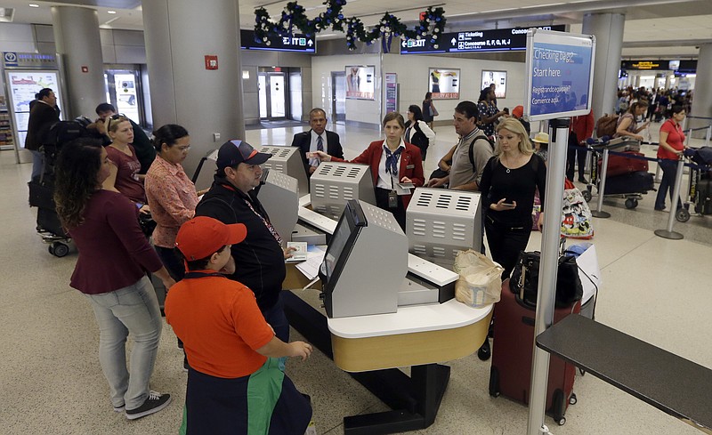 In this Nov. 25, 2015 file photo, travelers check in their luggage as they prepare to travel at Miami International Airport in Miami. A stronger economy and lower gas prices means Thanksgiving travelers can expect more highway congestions in 2015. Airlines for America, the lobbying group for several major airlines, forecasts 25.3 million passengers will fly on U.S. airlines, up 3 percent from last year.