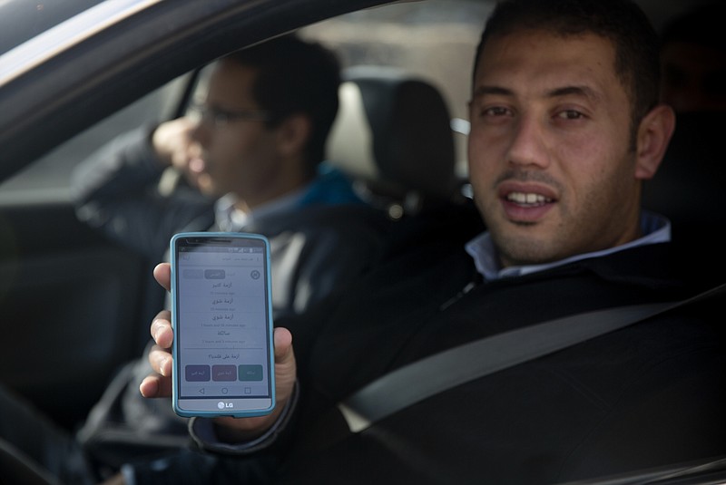 
              In this Tuesday, Nov. 10, 2015 photo, a Palestinian driver shows the “Azmeh” application, which means traffic jam in Arabic, on his mobile phone as he waits in traffic to enter Jerusalem at Qalandia checkpoint between Jerusalem and the West Bank city of Ramallah. A pair of new mobile apps hopes to help Palestinians navigate their way around snarled traffic at Israeli checkpoints in the West Bank, offering a high-tech response to an intractable problem: constant, burdensome and often seemingly random restrictions on movement. (AP Photo/Majdi Mohammed)
            