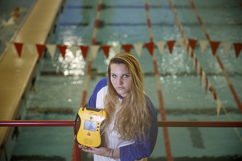 CSAS swimmer Cayce Grall holds an automated external defibrillator at the Baylor swimming pool, where her friend and fellow swimmer Sumner Smith died after a cardiac event during swim practice last month, on Wednesday, Nov. 18, 2015, in Chattanooga, Tenn. Grall is pushing for all of the area's public schools to have AEDs after Sumner's death.