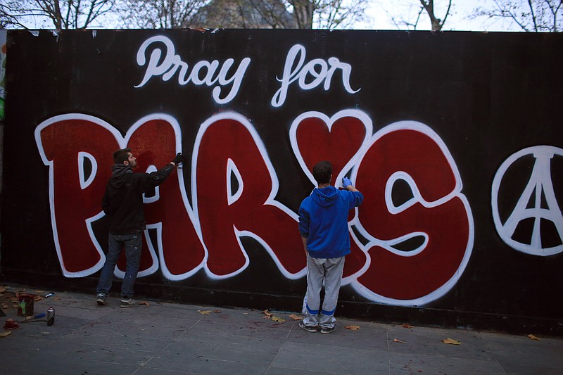 Two men paint a mural reads: "Pray for Paris" in tribute to the victims of the Paris attacks, in Paris, Saturday Nov. 14, 2015. French President Francois Hollande vowed to attack Islamic State without mercy as the jihadist group admitted responsibility Saturday for orchestrating the deadliest attacks inflicted on France since World War II. (AP Photo/Thibault Camus)