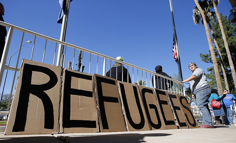 A sign welcoming Syrian refugees is placed at the entrance to the office of the Arizona governor during a rally at the Arizona Capitol on Tuesda in Phoenix. Arizona Gov. Doug Ducey has joined a growing number of governors calling for an immediate halt to the placement of any new refugees in the wake of terrorist attacks in Paris.