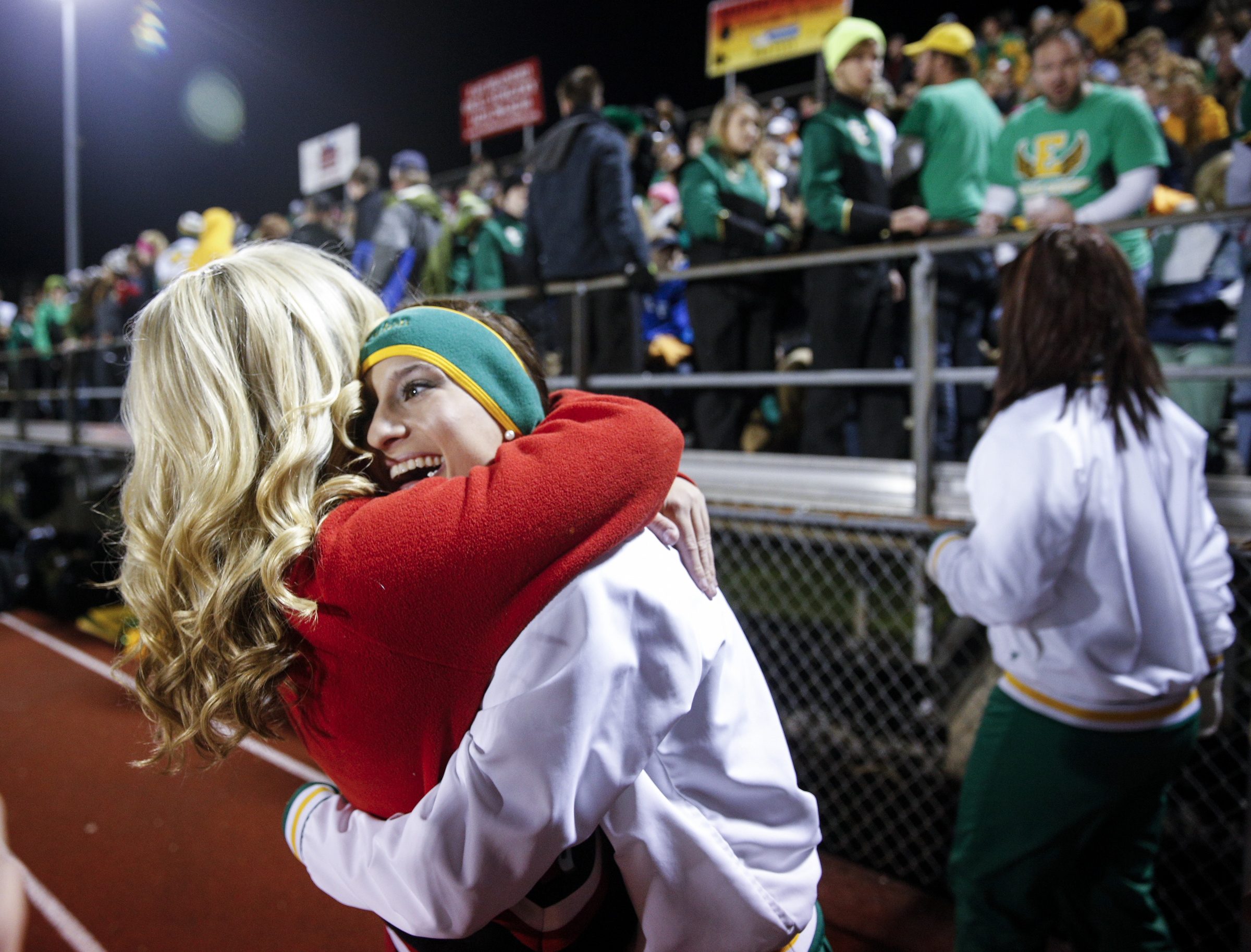 Rhea County cheerleader Peyton Carden, center, hugs Ooltewah cheerleader Chandler Patterson before their TSSAA prep football playoff football game at Ooltewah High School on Friday, Nov. 20, 2015, in Ooltewah, Tenn.