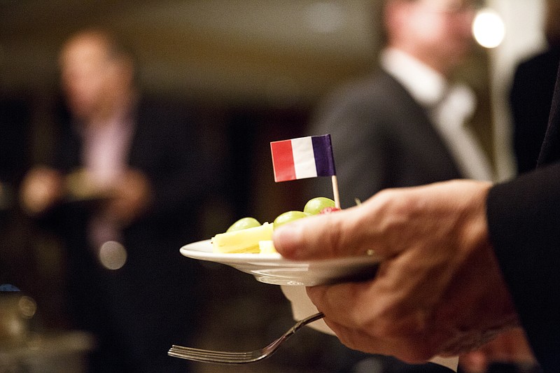 A french flag is placed in a toothpick on a plate at a gathering by the French American Chamber of Commerce to unveil a new wine at the Walden Club on Thursday, Nov. 19, 2015, in Chattanooga, Tenn. The event had already been planned before the terrorist attacks in Paris, but members of the chamber decided to hold a minute of silence to show solidarity with France and honor victims of the attacks.