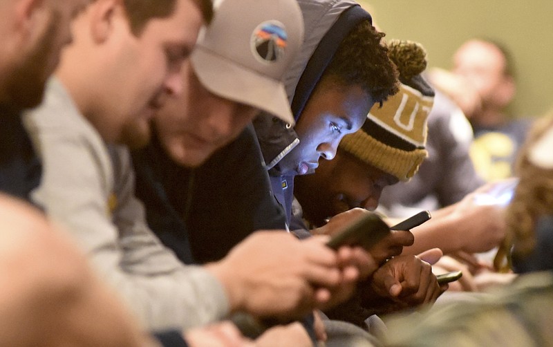 UTC defensive lineman Isaiah Mack, center, and other members of the football team use their phones in the auditorium in the Student Center on Sunday, Nov. 22, 2015, in Chattanooga, Tenn., after finding out their pairing in the 2015 NCAA Division I Football Championship. The Mocs learned that they will host Fordham at Finley Stadium on Saturday, Nov. 28 at 1 p.m.