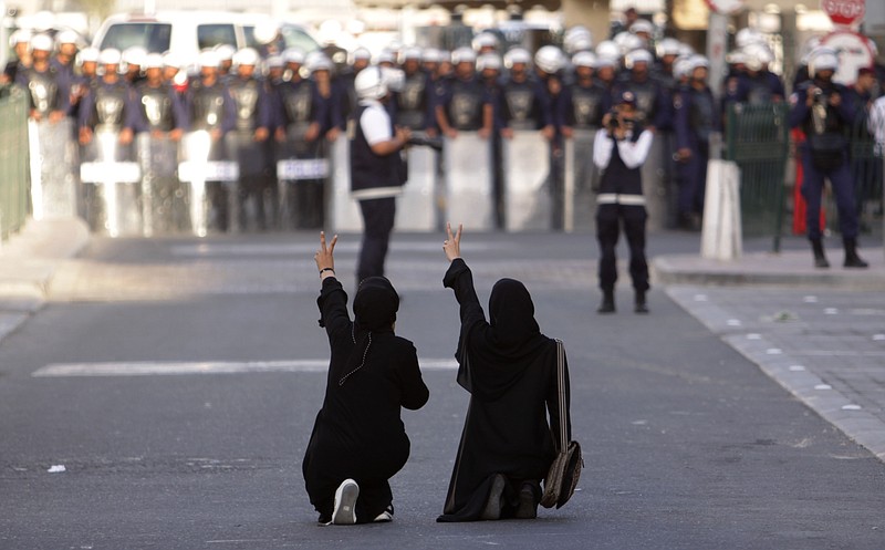 
              FILE- In this Wednesday, Jan. 18, 2012 file photo, Bahraini anti-government protesters kneel in the street and gesture toward riot police, in Manama, Bahrain. Bahrain’s security forces tortured detainees in the years after its 2011 protests despite a government promise to stop such abuses in the island nation, according to a new report released Monday. The Human Rights Watch report on Bahrain, home to the U.S. Navy’s 5th Fleet, corresponds with accounts of abuse provided by Amnesty International and local activists.(AP Photo/Hasan Jamali, file)
            