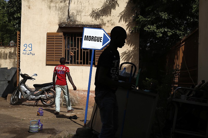 
              Hospital workers walk, outside the morgue of the Gabriel Toure hospital, in Bamako, Mali, Sunday, Nov. 22, 2015. The heavily armed Islamic extremists who shot up a luxury hotel in Mali's capital, killing 19 people, timed their assault for the moment when guards would be the most lax, allowing them to easily blast their way past a five-man security team before turning their weapons on terrified guests, a security guard and witnesses said Saturday.  (AP Photo/Jerome Delay)
            