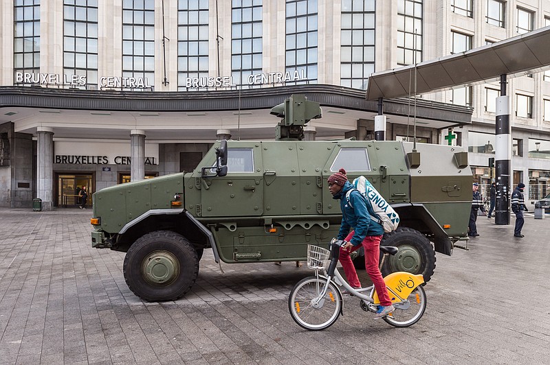 A man cycles by Belgian Army vehicle parked in front of the main train station in the center of Brussels on Sunday, Nov. 22, 2015.