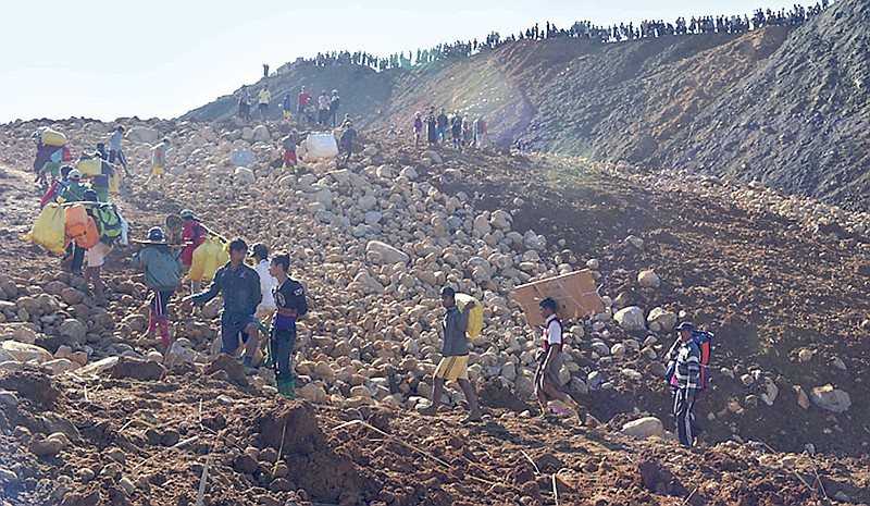 
              In this photo taken Saturday, Nov. 21, 2015 and released by Eleven Media Group, mine workers carrying their belongings walk after their houses were destroyed by a landslide in Phakant jade mine, Kachin State, Myanmar. The landslide near the jade mine in northern Myanmar killed up to many people and left many missing, most of them villagers sifting through a huge mountain of tailings and waste, a community leader and businessman said Sunday. (Eleven Media Group via AP) CREDIT MANDATORY
            