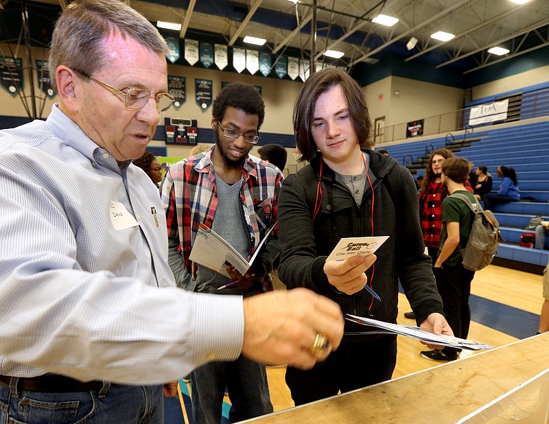 
              In this photo taken Tuesday, Nov. 17, 2015, Ed Davis, left, passes out curve ball cards to Siegel High School seniors Brandell Elston, center, and Alan Fessle, right during the UT simulation program "On My Own", at the school in Murfreesboro, Tenn.. The cards give a scenario where the person either receives money or has an unexpected bill. The program follows the concept of the board game "The Game of Life", where the students have to purchase items and have real world bills on a particular budget. (Helen Comer/The Daily News Journal via AP) NO SALES; MANDATORY CREDIT
            