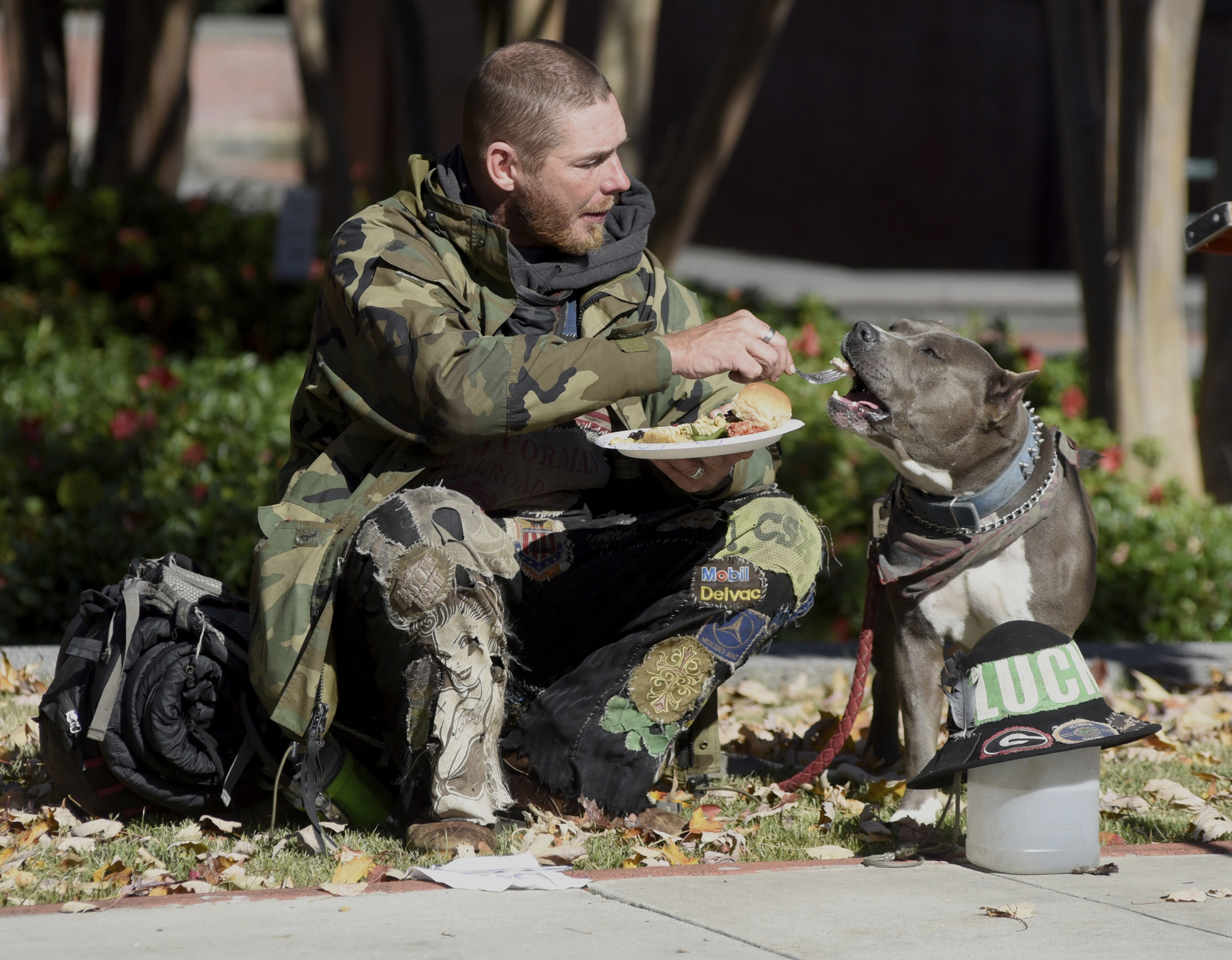 Lucky Johnson shares food with his dog, Blue, during the second annual One Table event Monday, Nov. 23, 2015, in Chattanooga, Tenn. Johnson said he is a hobo traveling by train from Colton, Calif., and that he and Blue arrived in Chattanooga on Sunday.