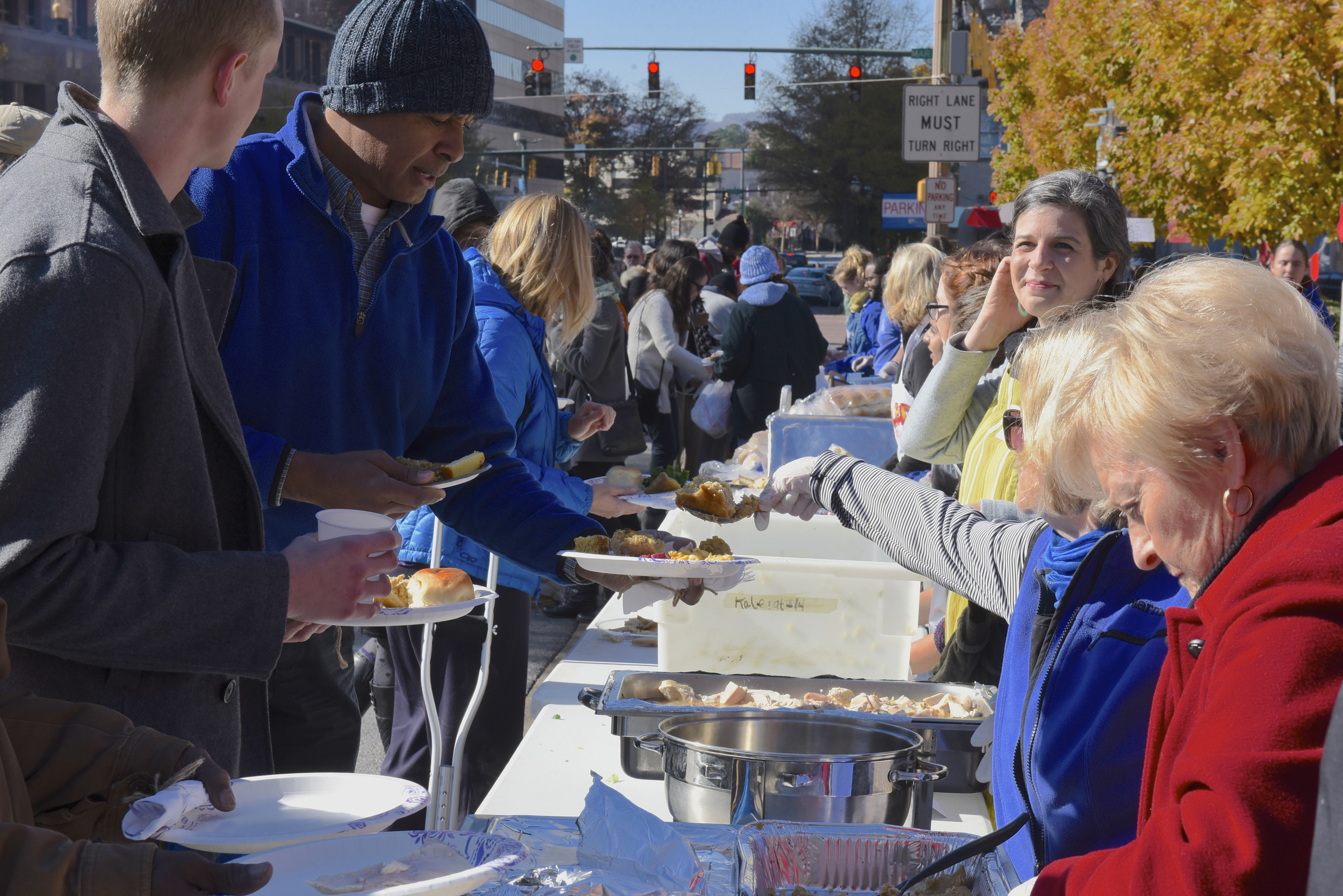 Volunteers serve food during the second annual One Table event Monday, Nov. 23, 2015, in Chattanooga, Tenn. The event features a Thanksgiving meal available to anyone, and is served on long table in the middle of ML King Boulevard in between Miller Park and Miller Plaza.