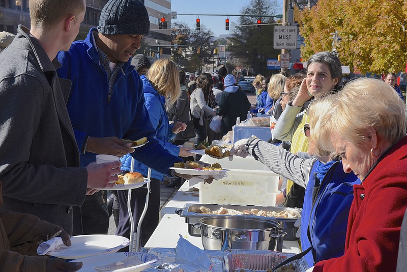 Volunteers serve food during the second annual One Table event Monday, Nov. 23, 2015, in Chattanooga, Tenn. The event features a Thanksgiving meal available to anyone, and is served on long table in the middle of ML King Boulevard in between Miller Park and Miller Plaza. 