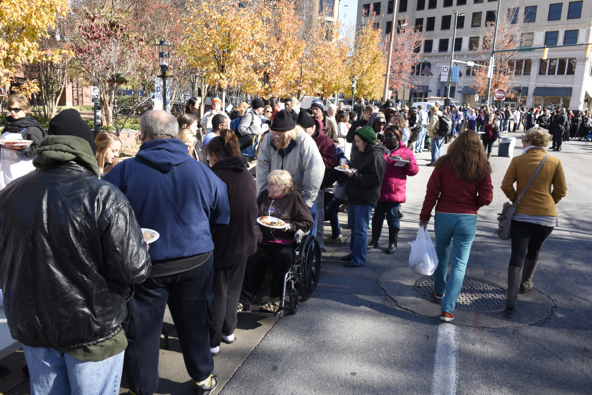 People eat during the second annual One Table event Monday, Nov. 23, 2015, in Chattanooga, Tenn. The event features a Thanksgiving meal available to anyone, and is served on long table in the middle of ML King Boulevard in between Miller Park and Miller Plaza.