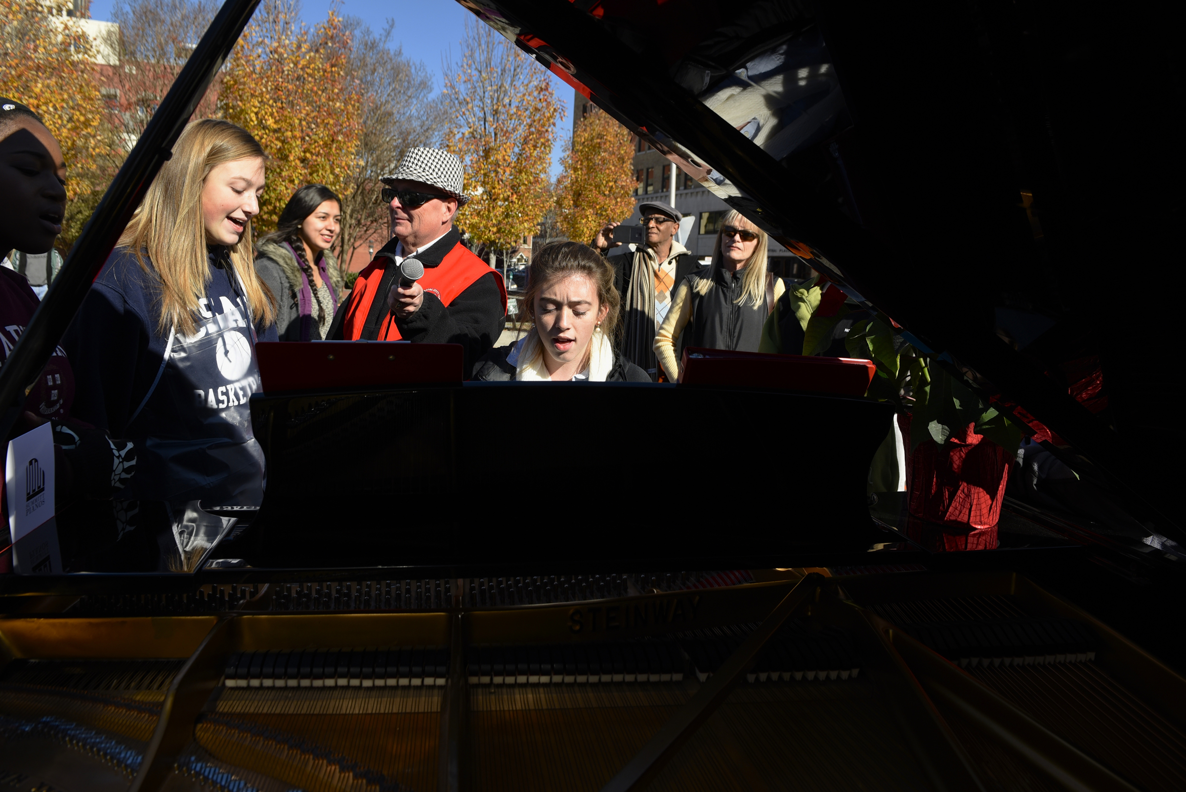 Emilee Swafford plays a Steinway grand piano while others gather around and join in to sing during the second annual One Table event in the middle of ML King Boulevard on Monday, Nov. 23, 2015, in Chattanooga, Tenn. The piano was furnished for the event by Summitt Pianos.