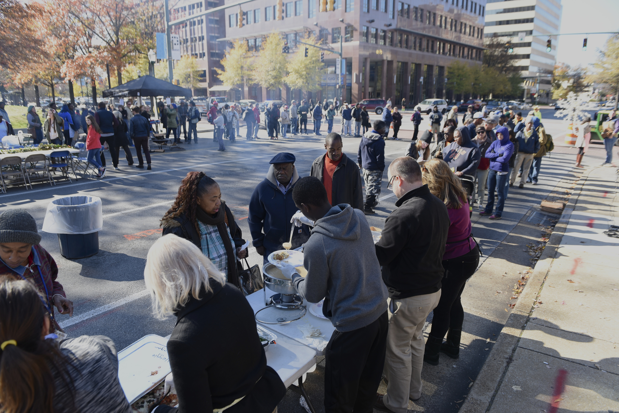 People line up for lunch during the second annual One Table event Monday, Nov. 23, 2015, in Chattanooga, Tenn. The event features a Thanksgiving meal available to anyone, and is served on long table in the middle of ML King Boulevard in between Miller Park and Miller Plaza.