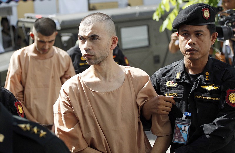 
              Police officers escort suspects in the Aug. 17 blast at Erawan Shrine, Bilal Mohammad, front, and Mieraili Yusufu, rear, as they arrive at a military court in Bangkok, Thailand, Tuesday, Nov. 24, 2015. The military court has indicted two men police say carried out the deadly August bombing at the shrine that left 20 people dead and more than 120 injured. (AP Photo/Sakchai Lalit)
            