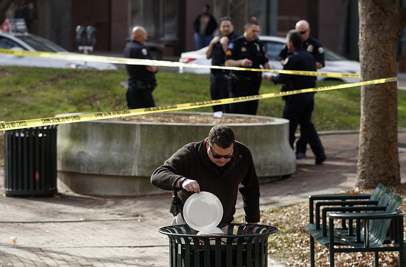 Investigator Christopher Blackwell looks inside a trash can at the scene of an early afternoon shooting in Miller Park on Tuesday, Nov. 24, 2015, in Chattanooga.