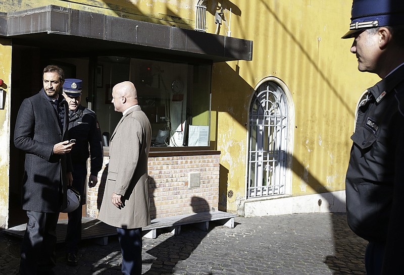 
              Italian journalists Gianluigi Nuzzi, center, and Emiliano Fittipaldi, left, talk with Vatican Gendarmie guards at the Perugino entrance of the Vatican, Tuesday, Nov. 24, 2015. The two Italian journalists who wrote books detailing Vatican mismanagement faced trial on Tuesday in a Vatican courtroom along with three people accused of leaking them the information in a case that has drawn scorn from media watchdogs. (AP Photo/Gregorio Borgia)
            
