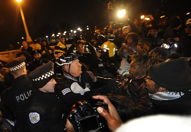 
              Chicago police officers struggle with protestors on Tuesday, Nov. 24, 2015, in Chicago. White Officer Jason Van Dyke, who shot a black teenager 16 times last year, was charged with first-degree murder Tuesday, hours before the city released a video of the killing. (AP Photo/Paul Beaty)
            