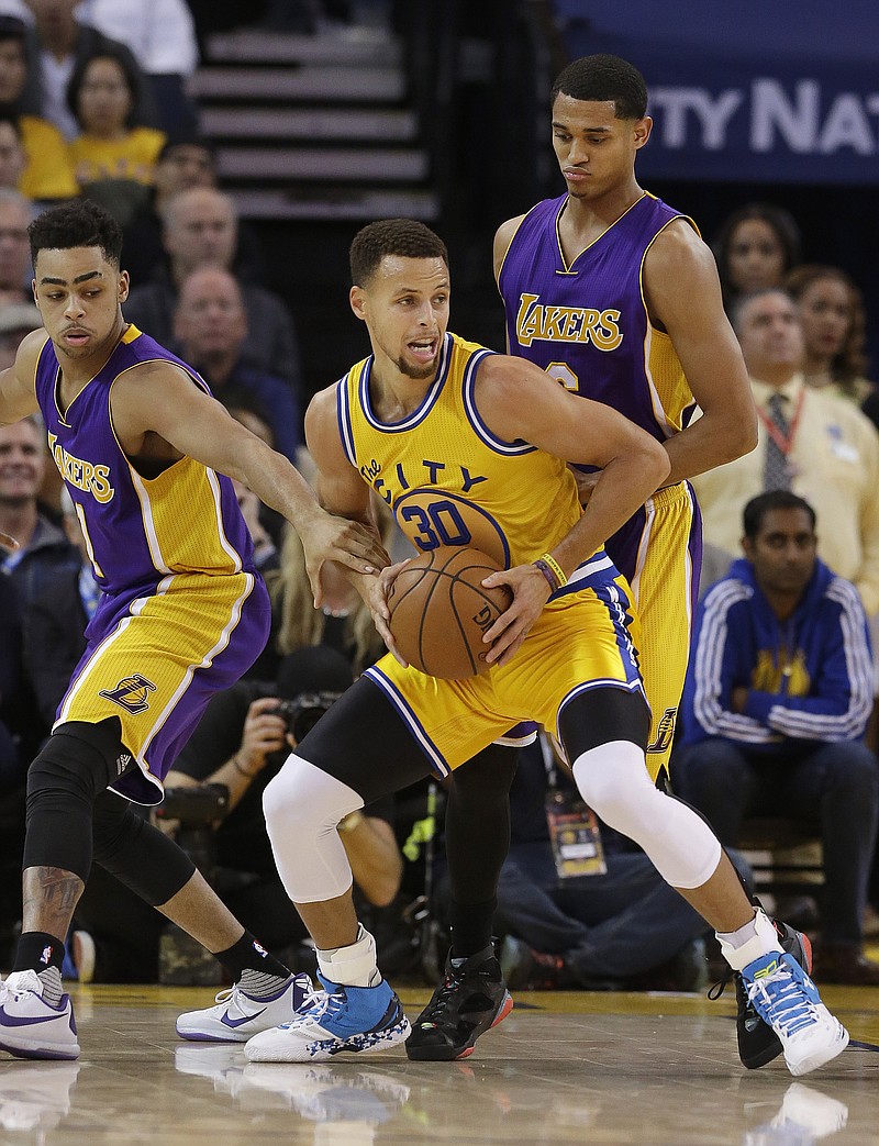 
              Golden State Warriors guard Stephen Curry (30) is defended by Los Angeles Lakers guards D'Angelo Russell, left, and Jordan Clarkson during the first half of an NBA basketball game in Oakland, Calif., Tuesday, Nov. 24, 2015. (AP Photo/Jeff Chiu)
            
