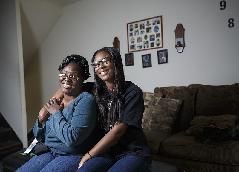 LaTonya Porter-Yost, left, and her daughter Chanel Mobley sit in the living room of their home for a portrait Wednesday, Nov. 25, 2015, in Chattanooga, Tenn. Porter-Yost, the sole provider for her family, received help from United Way after she was diagnosed with a life-threatening heart condition which forced her to leave work.