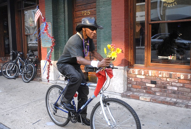 Sandy Bell rides down Cherry Street while making his rounds selling flowers in area bars and restaurants in this file photo.