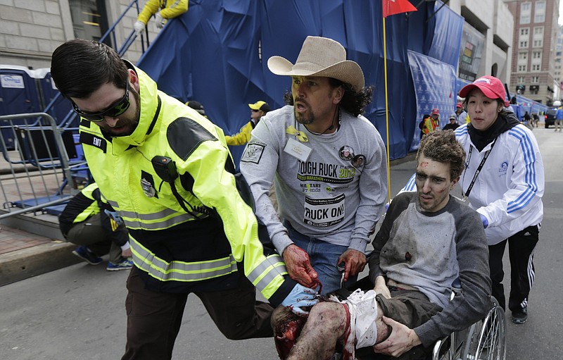 
              FILE - In this April 15, 2013, file photo, Boston Marathon bombing survivor Jeff Bauman is helped by Emergency Medical Services EMT Paul Mitchell, left, Carlos Arredondo, center, and Devin Wang, right, after he was injured in one of two explosions near the finish line of the Boston Marathon in Boston. Less than three years after bombs killed three people and wounded more than 260 others at the Boston Marathon, two movies, a documentary play and an HBO documentary are all in the works. Those most touched by the 2013 attack have decidedly mixed feelings about seeing the tragedy told on the stage and screen. (AP Photo/Charles Krupa, File)
            