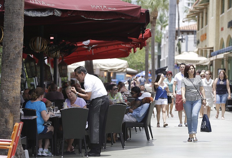 
              FILE - In this Friday, June 5, 2015, file photo, pedestrians walk along Lincoln Road Mall as people dine at sidewalk cafes, in Miami Beach, Fla. Americans were more optimistic about their incomes and personal finances in November 2015, particularly among lower and middle-class households, lifting consumers' outlook. (AP Photo/Lynne Sladky, File)
            