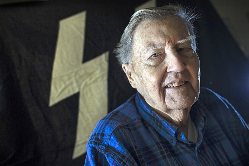 Hugh Montgomery, 91, poses for a photograph with the Nazi SS flag which was flying over Buchenwald concentration camp during WWII, in the background in his McLean, Va., home, Tuesday, Nov. 24, 2015. Montgomery went behind enemy lines for the OSS, where he was among the first Americans to enter the Buchenwald concentration camp. After returning to Harvard to earn his PhD and teach, he joined the newly formed CIA, where he led spying operations against the Soviets for decades, doing tours in Rome, Paris and Moscow. (AP Photo/Cliff Owen)