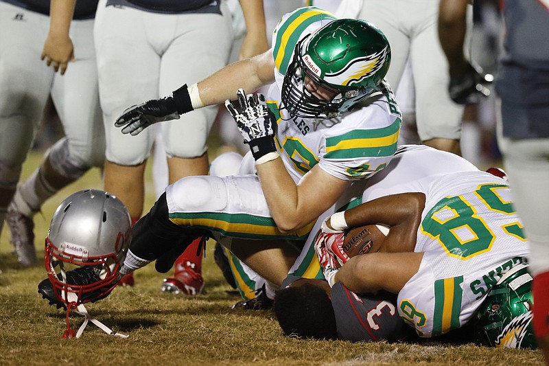 Rhea County's Tyler Pendleton (40) knocks the helmet off of Ooltewah's Cameron Turner (33) during the first half of play at the Owl's home field on Friday, September 18, 2015. 
