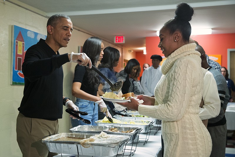 
              President Barack Obama, from left, Malia Obama, and first lady Michelle Obama serve Thanksgiving dinner during "Feast with Friends" at Friendship Place homeless center, on Wednesday, Nov. 25, 2015, in Washington. Friendship Place works with homeless and at-risk veterans in its Veterans First program. (AP Photo/Evan Vucci)
            