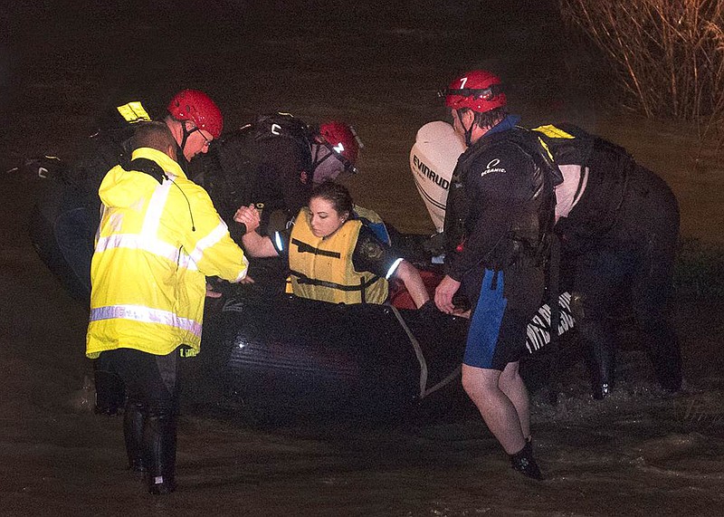 
              Firefighters assist Tarrant County Sheriff's Deputy Krystal Salazar after they rescued her from the raging waters of Deer Creek early Friday, Nov. 27, 2015, in Fort Worth, Texas. Salazar had gone into the water to attempt to rescue two other people that were swept away in the rushing waters, according to the Fort Worth Star-Telegram. The search continued for the missing people. (Glen E. Ellman/Star-Telegram via AP)  MAGS OUT; (FORT WORTH WEEKLY, 360 WEST); INTERNET OUT; MANDATORY CREDIT
            